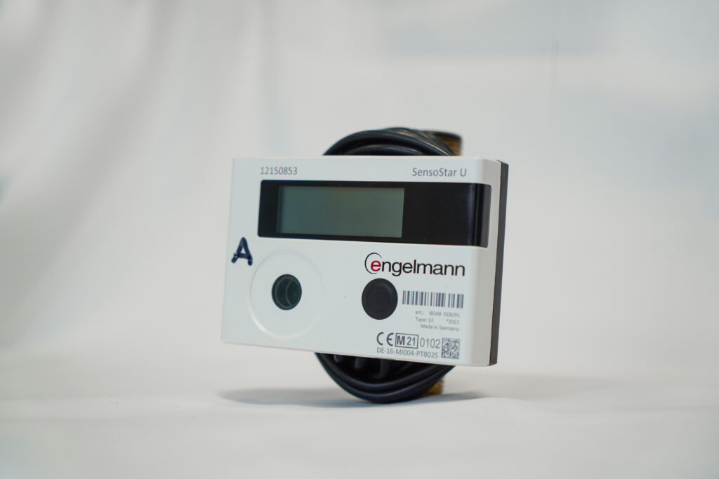 Technicien installant un compteur d'énergie thermique (CET) connecté sur un réseau de chauffage, illustrant la mise en place de la télérelève et du suivi des consommations énergétiques - OCEA Smart Building