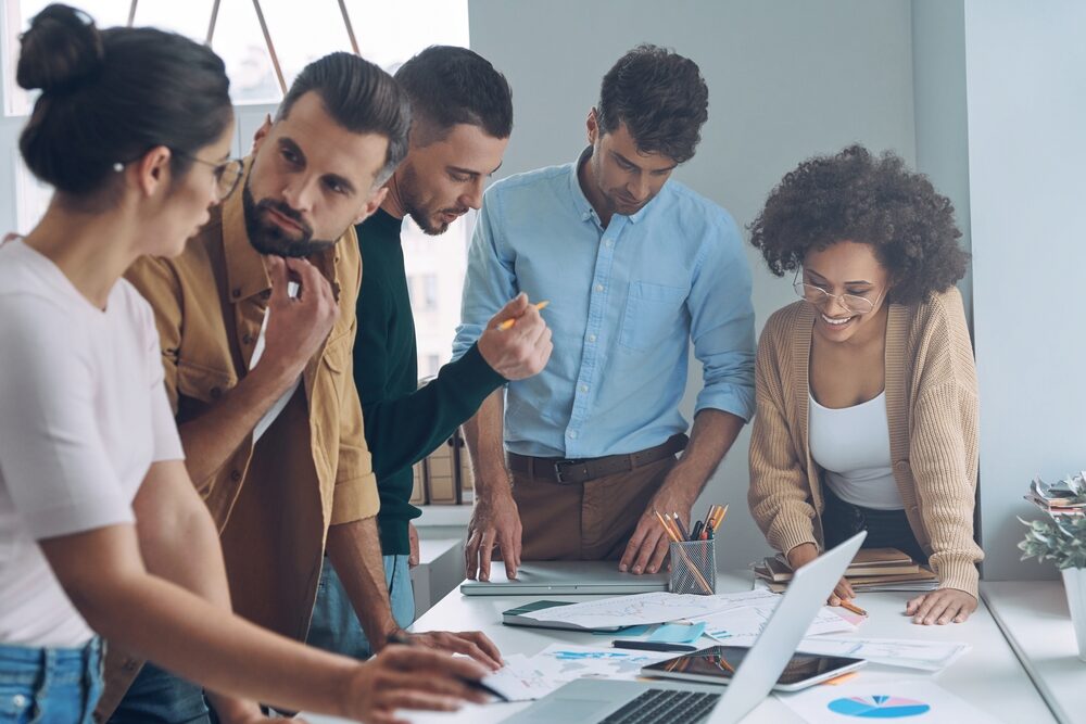 Équipe OCEA Smart Building en réunion de travail autour de plans et d’un ordinateur, illustrant la proximité, la réactivité et l’accompagnement client sur le terrain