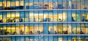 Immeuble de bureaux moderne avec espaces de travail visibles à travers la façade vitrée, illustrant le pilotage des consommations d’énergie et l’optimisation des charges dans les bâtiments tertiaires – OCEA Smart Building & Groupe OCEA
