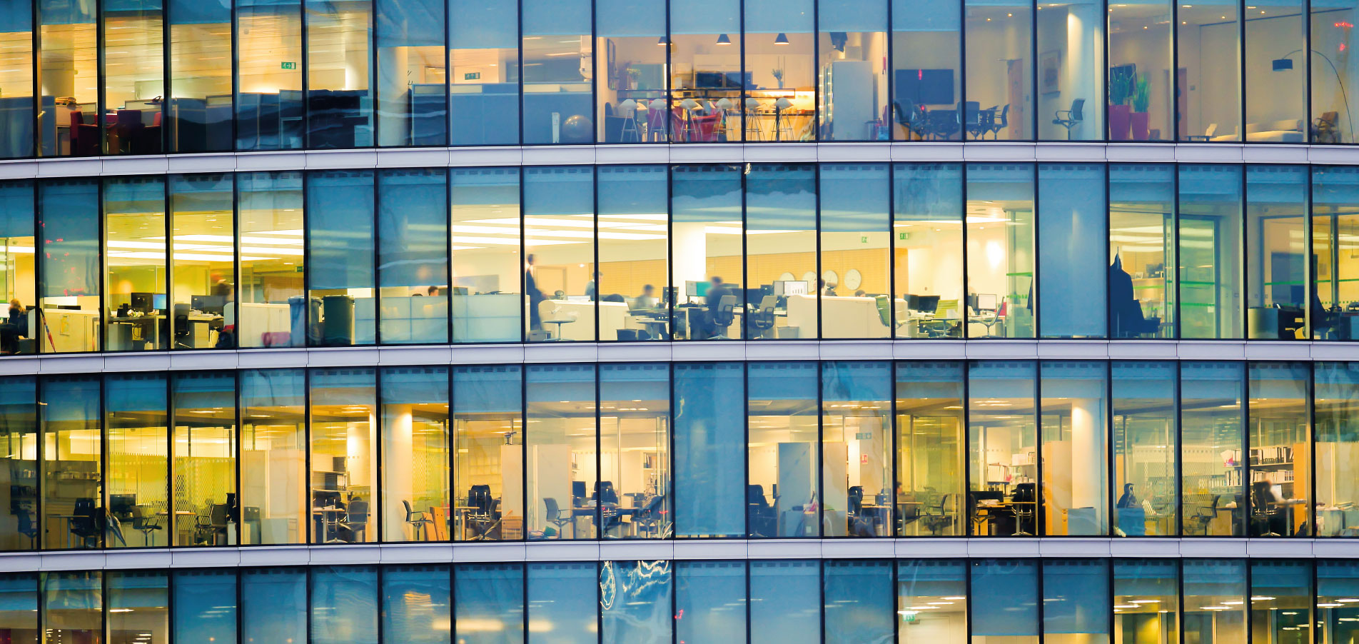 Immeuble de bureaux moderne avec espaces de travail visibles à travers la façade vitrée, illustrant le pilotage des consommations d’énergie et l’optimisation des charges dans les bâtiments tertiaires – OCEA Smart Building & Groupe OCEA