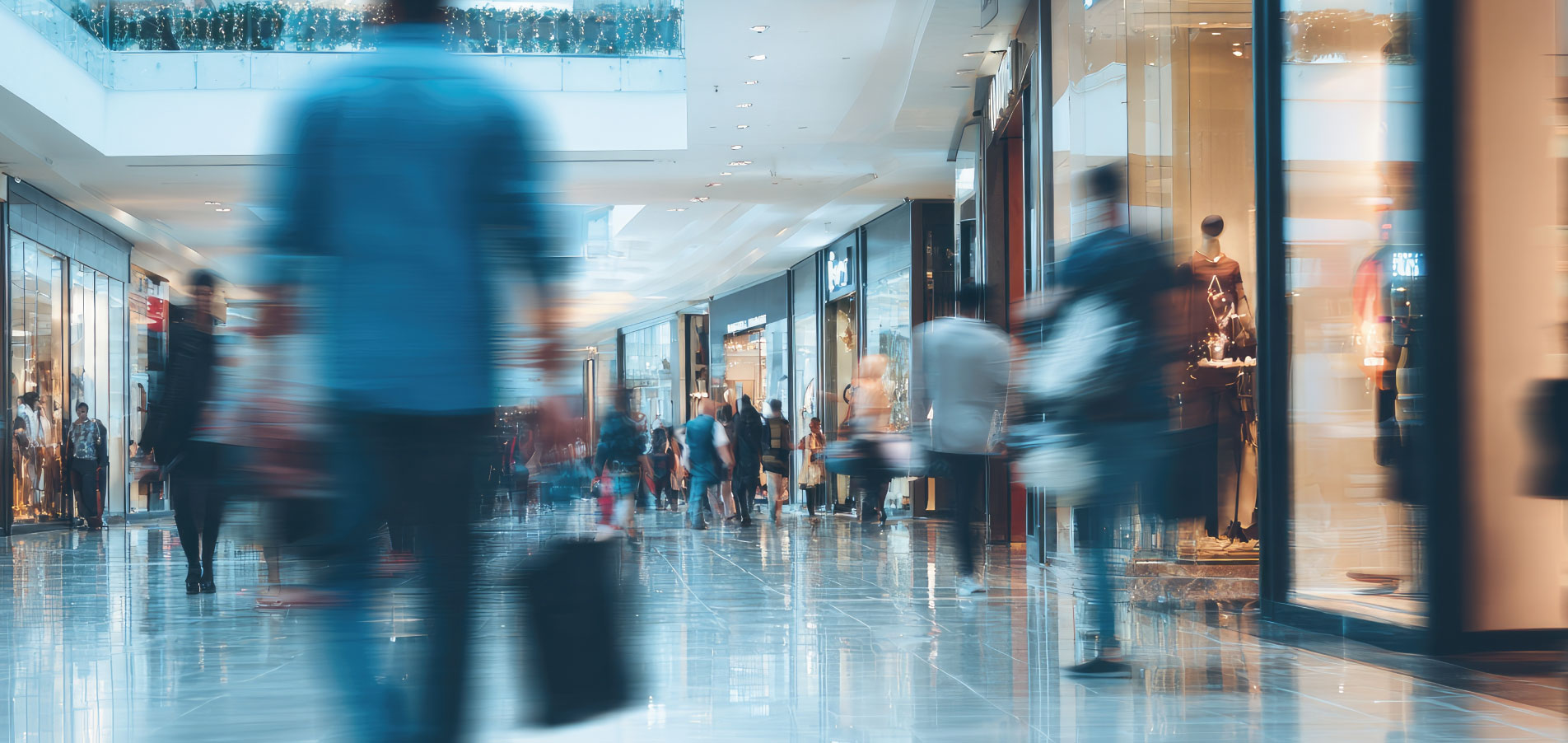 Centre commercial animé avec escalators et visiteurs en mouvement, illustrant la gestion des flux, la maîtrise des consommations d’énergie et l’optimisation des charges dans l’immobilier commercial et retail – OCEA Smart Building & Groupe OCEA
