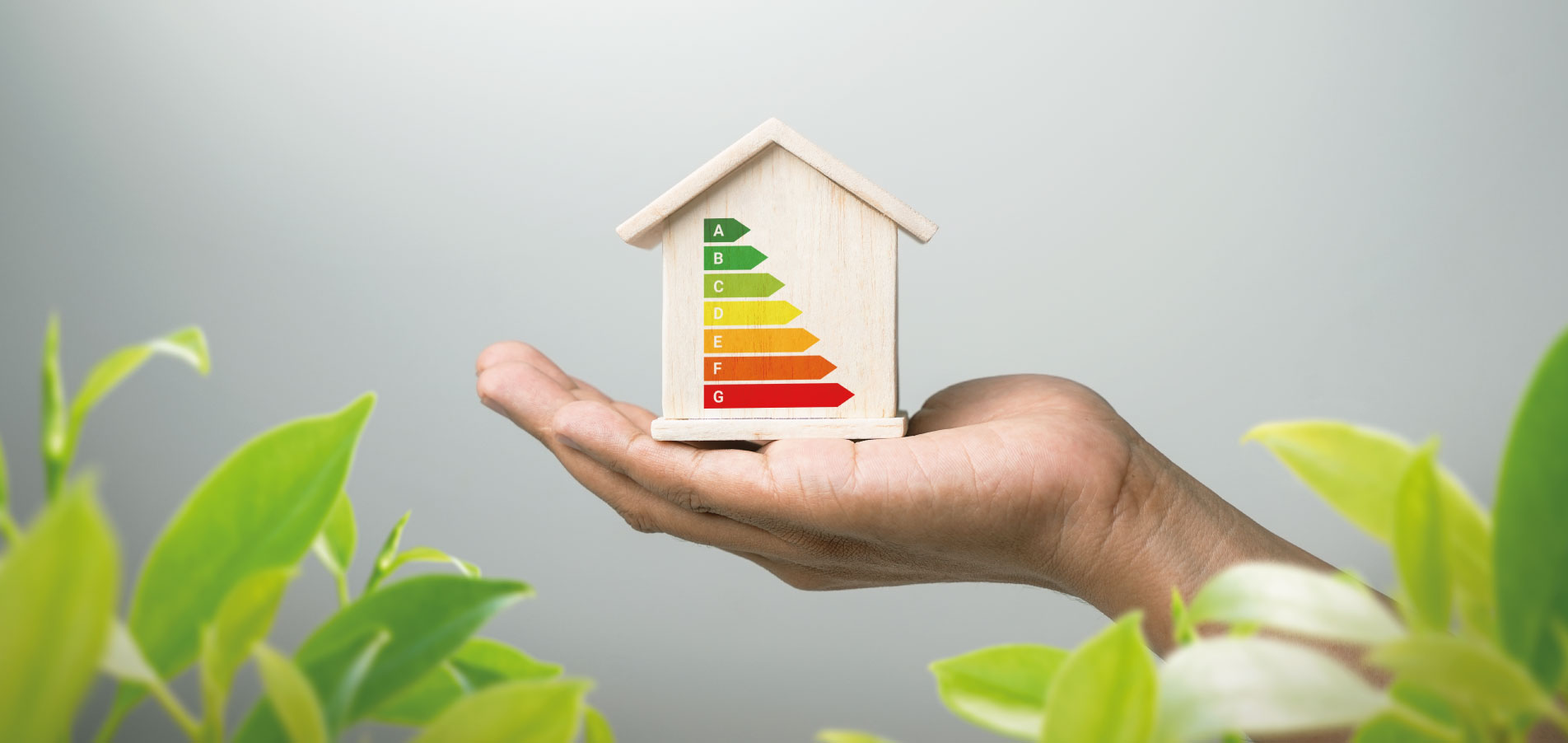Main tenant une maquette de maison avec étiquette énergétique, illustrant la réduction de l’empreinte carbone, l’amélioration de la performance énergétique et la valorisation du patrimoine immobilier - OCEA Smart Building - Géothermie