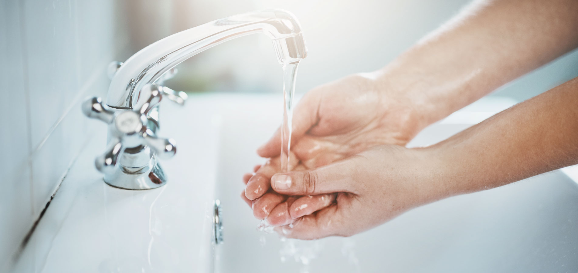 Mains sous un robinet avec écoulement d’eau, illustrant le suivi, la maîtrise et la détection des consommations d’eau dans le logement grâce à des solutions connectées et l'installation de compteurs d'eau individuels dans l'habitat collectif avec OCEA Smart Building