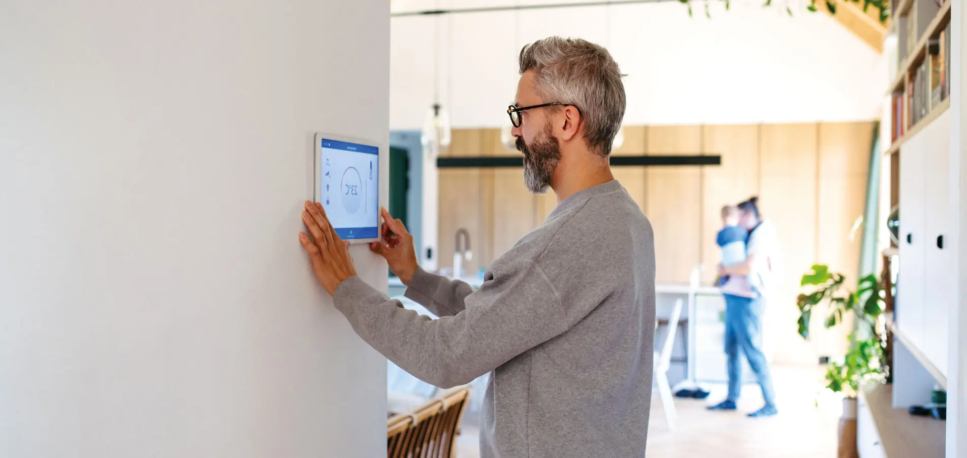 Copropriétaire ou occupant ajustant un thermostat connecté dans un logement moderne, illustrant l’optimisation des consommations énergétiques et l’amélioration du confort des occupants grâce au pilotage intelligent - Groupe OCEA - OCEA Smart Building