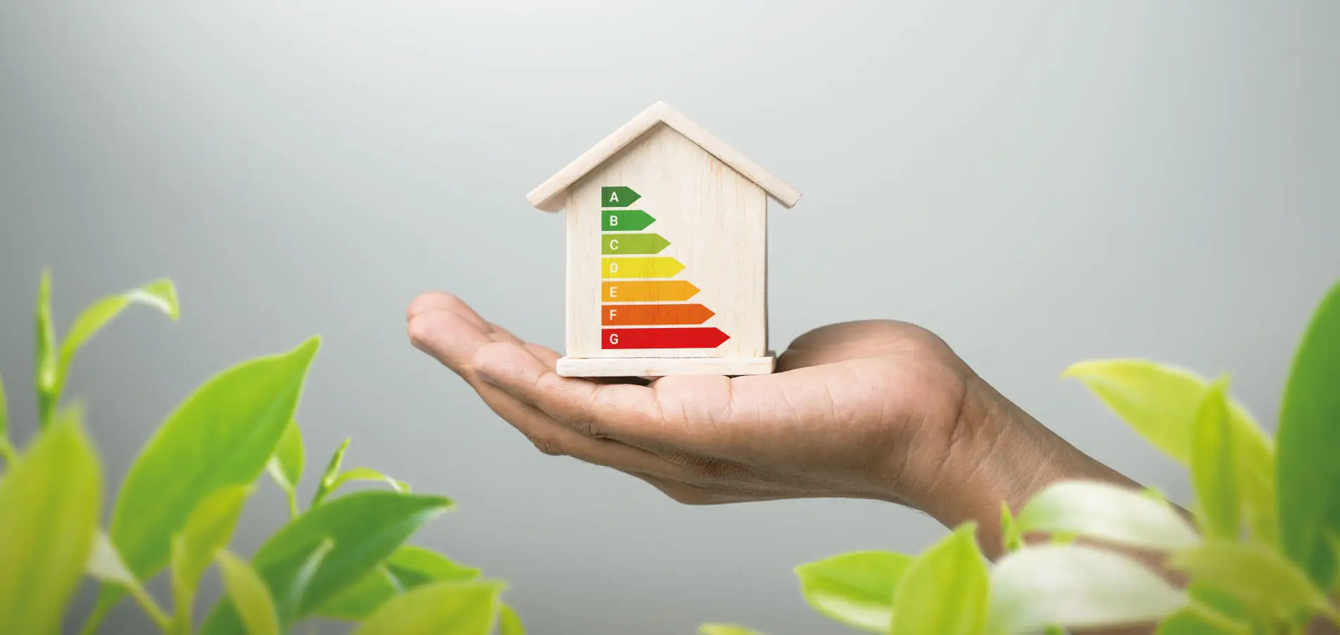 Main tenant une maquette de maison avec étiquette énergétique, illustrant la réduction de l’empreinte carbone, l’amélioration de la performance énergétique et la valorisation du patrimoine immobilier - OCEA Smart Building - Géothermie
